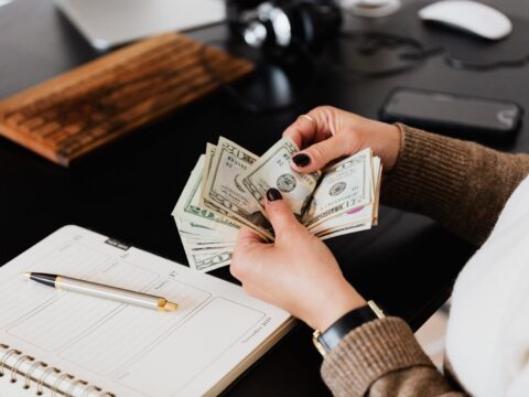 crop woman counting money at modern office table